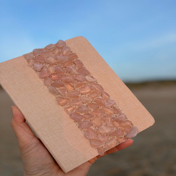 Liniertes Notizbuch (14 x 10 cm) mit echten Rosenquarz-Steinen, energetisiert mit REIKI-Energie; fördert Intuition, Schutz, Klarheit und Selbstvertrauen. Jedes Notizbuch ist einzigartig durch individuelle Steinmuster und spirituelle Aufladung.