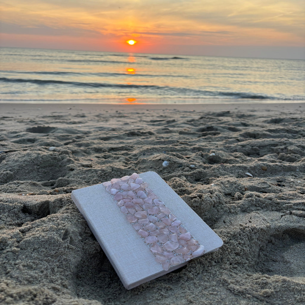 Liniertes Notizbuch (14 x 10 cm) mit echten Rosenquarz-Steinen, energetisiert mit REIKI-Energie; fördert Intuition, Schutz, Klarheit und Selbstvertrauen. Jedes Notizbuch ist einzigartig durch individuelle Steinmuster und spirituelle Aufladung.